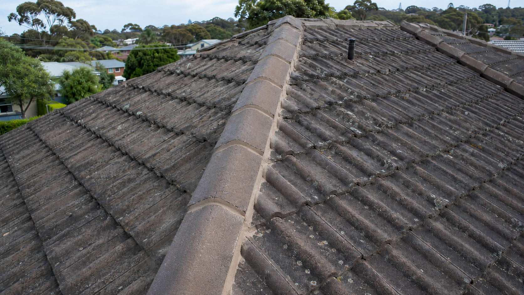 Close-up roof inspection showing ridge capping and tile condition assessment